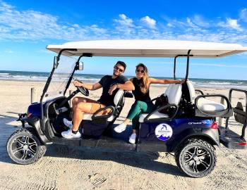 A pair of Life in Paradise guests pose on their Port Aransas golf carts rentals.