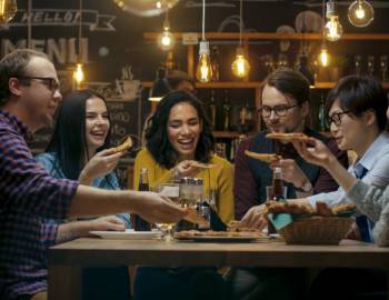 Groups of friends gather around the table at a Port Aransas pizza restaurant. 